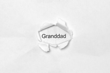 Word Granddad on white isolated background, the inscription through the wound hole in paper. Stock photo for web and print with empty space for textの写真素材