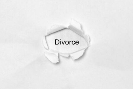 Word Divorce on white isolated background, the inscription through the wound hole in paper. Stock photo for web and print with empty space for textの写真素材