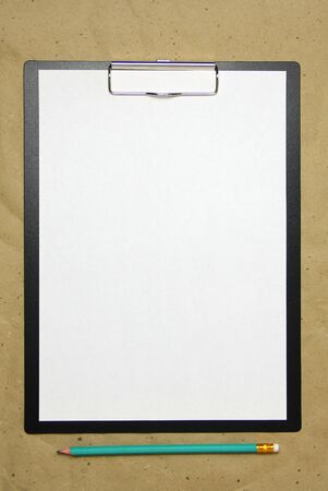 A tablet with a white sheet of A4 format with pencil on a beige craft paper. Concept of new opportunities, ideas, undertakings, innovations. Stock photo with empty place for your text and design.の写真素材