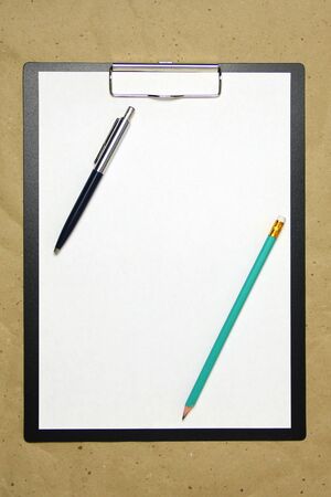 A tablet with a white sheet with pen and pencil on a beige craft paper. Concept of new opportunities, ideas, undertakings, innovations. Stock photo with empty place for your text and design.の写真素材