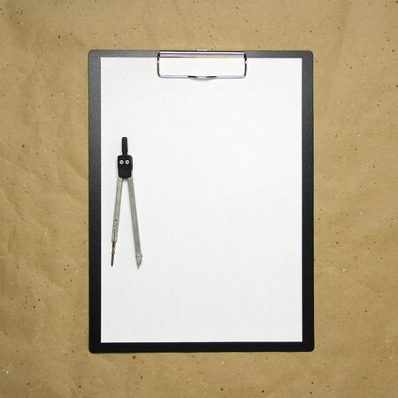 A tablet with a white sheet of A4 format with divivder on a beige craft paper. Concept of accurate measurements, study and construction. Stock photo with empty place for your text and design.の写真素材