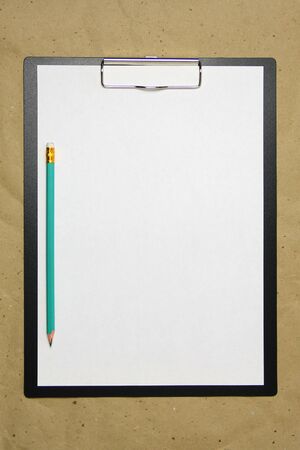 A tablet with a white sheet of A4 format with pencil on a beige craft paper. Concept of new opportunities, ideas, undertakings, innovations. Stock photo with empty place for your text and design.の写真素材