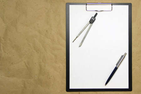 A tablet with a white sheet of A4 format on a beige craft paper with pen and divider. Concept of...