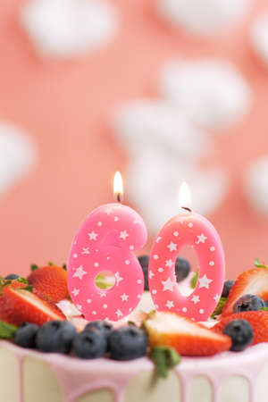 Birthday cake number 60. Beautiful pink candle in cake on pink background with white clouds....