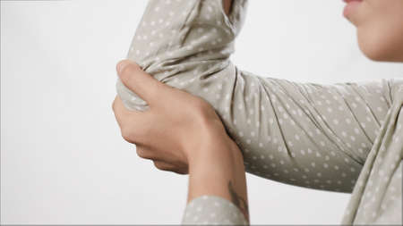 Elbow pain. Female hand touches elbow on white background. Close-upの写真素材