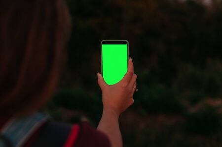 Beautifull young girls hand holding smartphone with blank screen. Green blank screenの写真素材