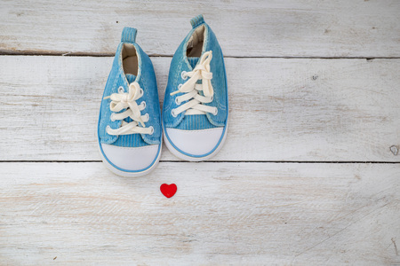 small baby blue sneakers on a white wooden background. baby shoesの写真素材