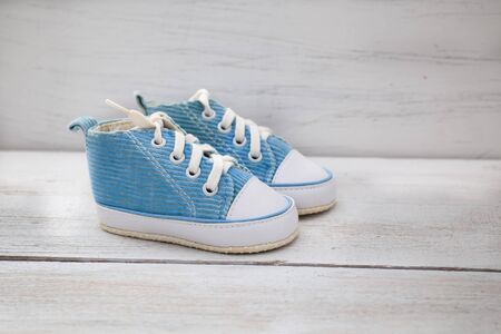 blue shoes for baby boy on a white wooden backgroundの写真素材