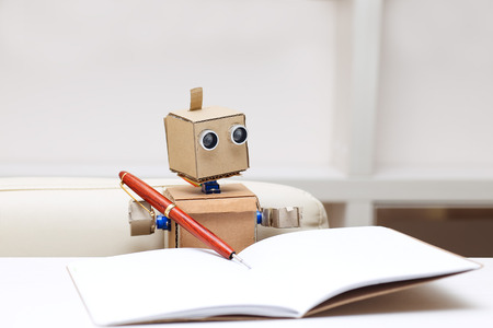 Robot writes sitting at table in writingの写真素材