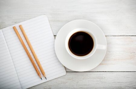 white desk with cup of coffee,pencil; notebook. lay flatの写真素材