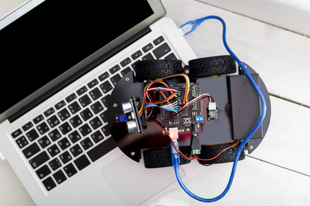 robot on four wheels connected to the laptop via the blue wire. View from above