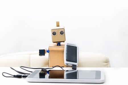 Robot holds a solar battery connected to the tabletの写真素材