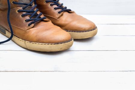 Old brown boots on a white wooden backgroundの写真素材