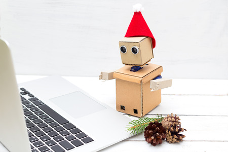 Robot in a New Year's hat working on a laptopの写真素材