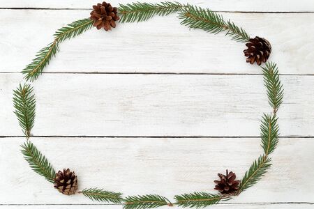 Frame in the shape of an oval of twigs of a Christmas tree on a wooden background. Flat layの写真素材