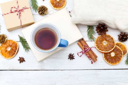 A cup of hot tea is on the book, and around the Christmas decorations on a wooden background. Flat layの写真素材