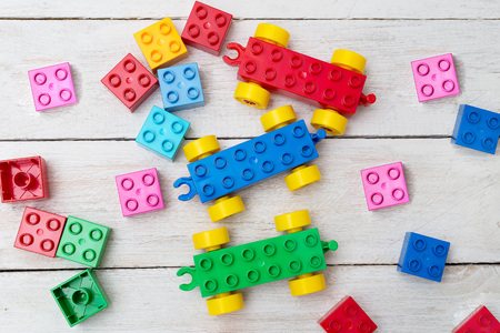 Bright plastic construction blocks on wooden background. Developing toys. Early learning.の写真素材