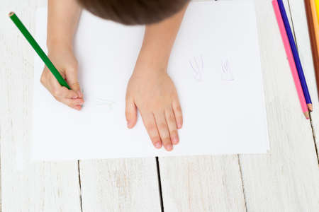 The child paints with colorful jellyfish pencils on paper. Flat layの写真素材
