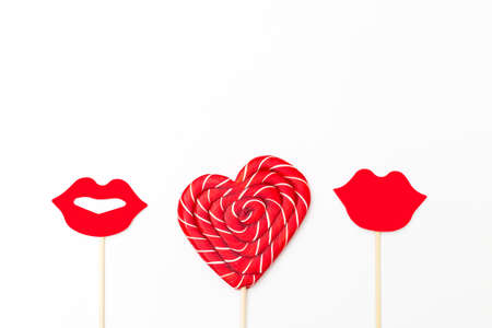 Valentine concept. Lollipop in the shape of a red heart and lips on a white backgroundの写真素材