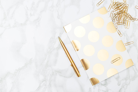 Notebook and stationery items of gold color. Feminine desktop.の写真素材