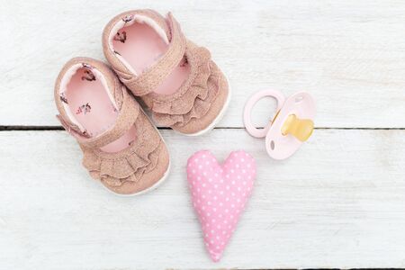 Shoes and pacifier pink for the little girl on a wooden background. Flat layの写真素材
