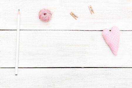 Handmade mock up. Threads and pink soft heart on white wooden backgroundの写真素材
