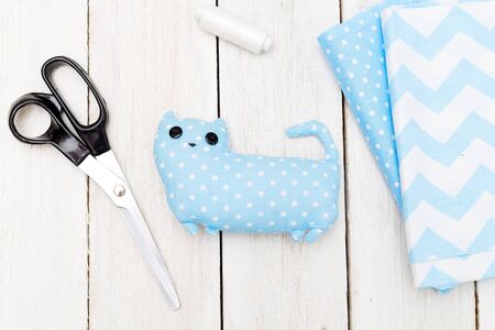 Blue toy cat on a white wooden background. Handmade