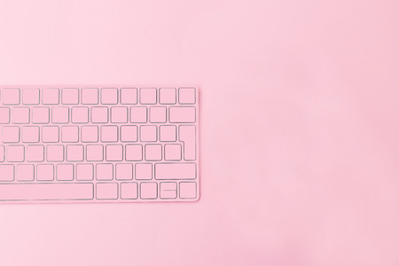 Cup of coffee and keyboard on a pink background. Coffee breakの写真素材