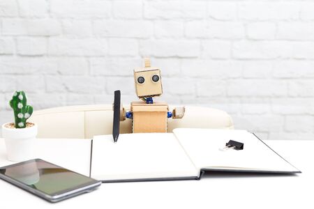 The robot with his hands writes a pen in his notebook. Artificial Intelligenceの写真素材