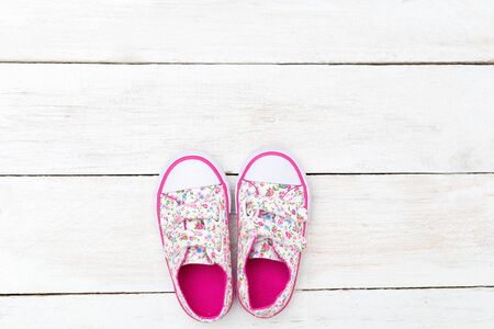Pink sneakers for little girl on white wooden background. Flat layの写真素材