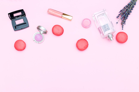 Set of cosmetics and strawberry macaroons on a pink background. Copy spaceの写真素材