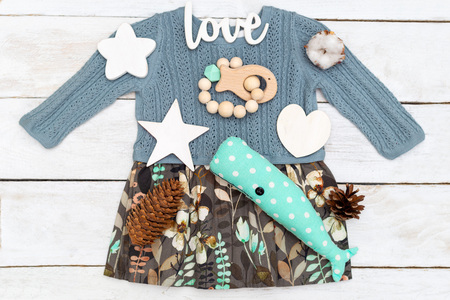 Baby girl clothes and toys on a wooden background. Flat lay
