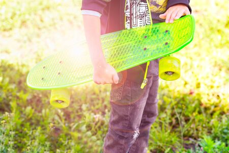 Boy skater holds in his hand a neon green skateboard. Outdoorsの写真素材