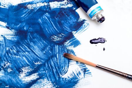 Tube of blue  paint and blue paint strokes on white background. Flat lay. Color 2020の写真素材