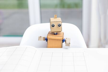 Cardboard robot sitting at the table at home. Artificial intelligenceの写真素材