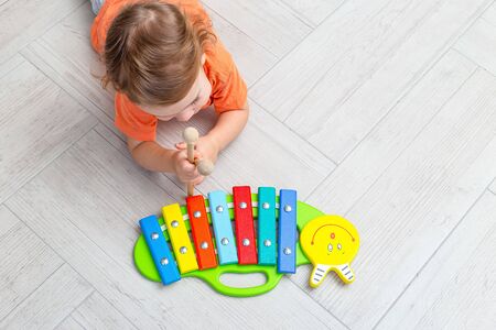 A child plays in a wooden multi-colored xylophone at home. Flat layの写真素材