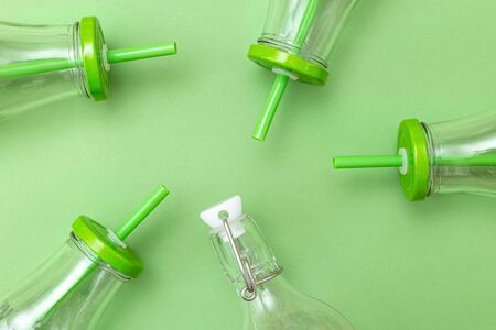 Glass bottle with a straw in green on a green background. Monochrome. Zero waste. Backgroundの写真素材
