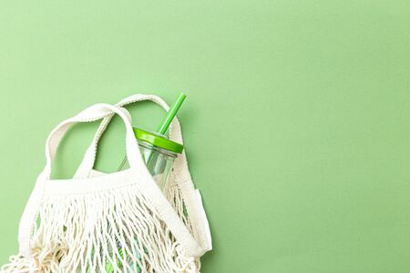 Glass bottle and net bag on a green background. Copy space. Monochrome. Zero wasteの写真素材
