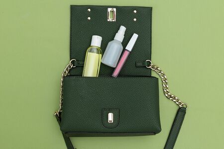 Green hand bag with  lip gloss and antiseptic on green background. Green monochrome.の写真素材