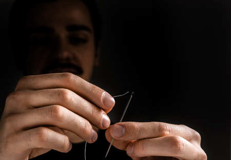 Man tailor threading a needleの写真素材