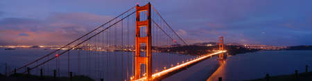 Glowing cheerful red Golden Gate bridge on a stormy evening in winter with San Francisco sky line...