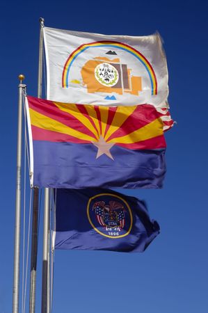 Flags of Utah, Arizona and Navajo Nation are whipped by a strong wind above Monument Valley Visitor Center. A small fragment of Stars-and-stripes is visible too.の写真素材