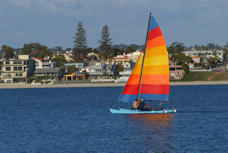 Two men are sailing a yacht with colorful sail in Mission Bay, San Diego, California.の写真素材