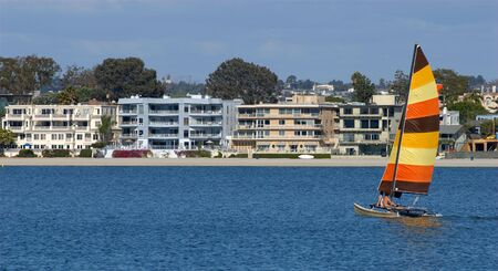 A young couple is sailing towards condominiums in Mission Bay, San Diego, California. A perfect metaphor for sailing to first home ownership through the sea of life.の写真素材