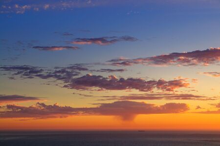 Majestic sunset over Pacific Ocean with a silhouette of a lonely ship far off and a rain squall visible in the distance.の写真素材