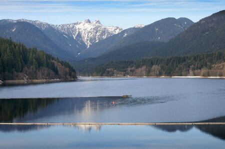 The Lions (peaks) reflected in Capilano Lake, North Vancouver on a winter day.の写真素材