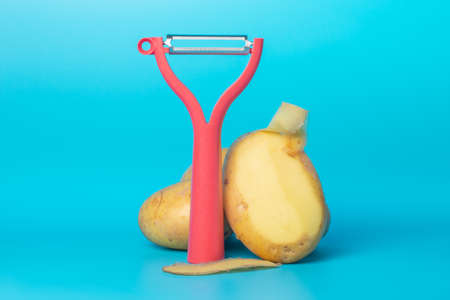 Red vegetable peeler and vegetablesの写真素材