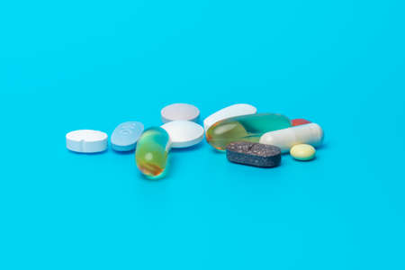 Selection of daily pills on a blue background. Different shapes and colorsの写真素材