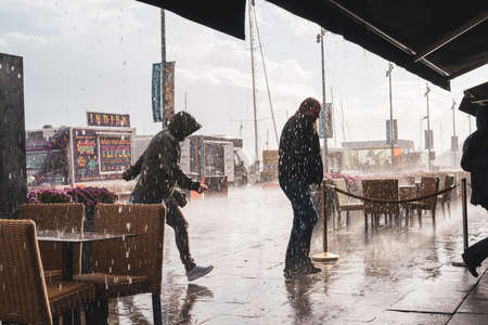 Oslo.Oslo/Norway-09.17.2020: Silhouette of a man caught in a strong rain in Oslo, Aker Brygge.のeditorial素材