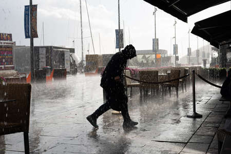 Oslo.Oslo/Norway-09.17.2020: Silhouette of a man caught in a strong rain in Oslo, Aker Brygge.のeditorial素材